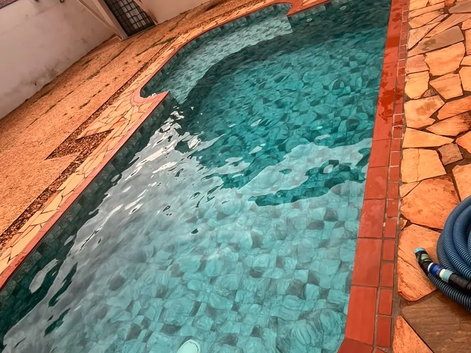 Piscina de pastilha verde-água com borda de tijolo