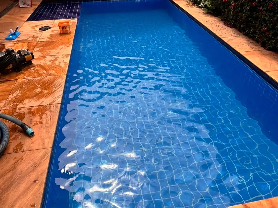 Piscina azul com bomba e aspirador na borda